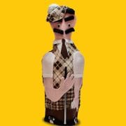 A man in plaid shirt and tie standing next to a yellow wall.