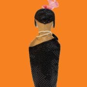 A woman in black dress with pink bow on head.