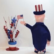 A toy uncle sam with american flags and stars.